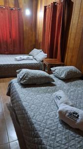 3 Betten in einem Zimmer mit roten Vorhängen in der Unterkunft Cabañas El Okaso del Sol in Santa Cruz
