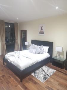 a bedroom with a large bed with white sheets and pillows at Lux 2 Bed Flat in Canary Wharf in London