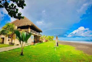 a person standing in front of a house on the beach at Hotel Pazifico en Monterrico in Monterrico