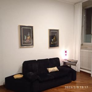 ein Wohnzimmer mit einer schwarzen Couch in einem Zimmer in der Unterkunft Appartamento Crisopoli in pieno centro a Parma in Parma