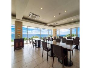 a dining room with tables and chairs and windows at Hotel Hamahigashima Resort - Vacation STAY 10606v in Uruma