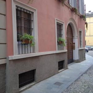 ein rosafarbenes Gebäude mit zwei Fenstern und zwei Topfpflanzen in der Unterkunft Appartamento Crisopoli in pieno centro a Parma in Parma