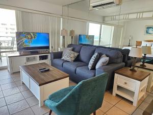 uma sala de estar com um sofá azul e uma televisão em Ilikai Tower 1533 Yacht Harbor View 1BR em Honolulu