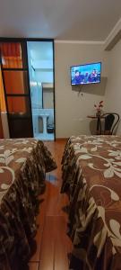 a bedroom with a bed and a tv on the wall at Hostal Bryan in Tacna