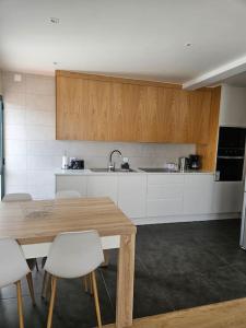a kitchen with a wooden table and white cabinets at Pedreira apartment in Calheta