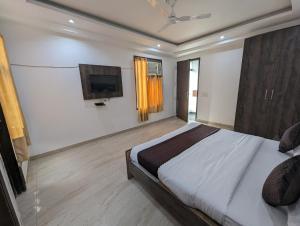 a bedroom with a bed and a flat screen tv at Hotel Aron By The Premium Villa in New Delhi