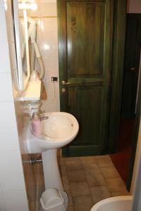 a bathroom with a white sink and a green door at A La Casa Dei Potenti in San Gimignano
