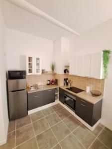 La cuisine est équipée de placards blancs et d'un réfrigérateur noir. dans l'établissement Appartement lumineux , Carpentras centre, à Carpentras