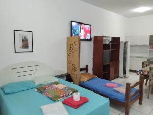 Cette chambre comprend 2 lits, une table et une télévision. dans l'établissement Seu Apto Praia da Costa 3 Não divide Completo Ar Cond Fogão Geladeira Internet Local Excelente Centro Sem escadas, à Vila Velha