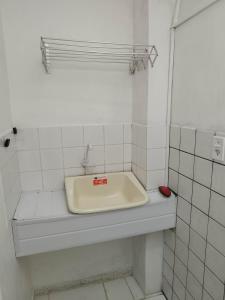 a white tiled bathroom with a sink on a counter at Seu Apto na Praia da Costa 3 Todo seu Completo Ar Cond Fogão Geladeira Internet Local Excelente Centro Sem escadas in Vila Velha