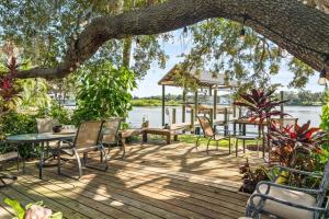 a wooden deck with chairs and a table and a tree at Riverfront Oasis Stunning Inside and Out Remodeled 3BR Riverfront Home with Hot Tub and personal paddle boats with Access to the Gulf in Riverview