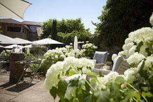 un jardín con flores blancas, sillas y sombrillas en Die Reichsstadt - Hotel Spa und Restaurant, en Gengenbach