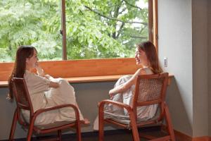 duas mulheres sentadas em cadeiras olhando para fora de uma janela em Towadakohan Sakura - Vacation STAY 03811v em Towada