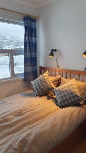 ein Schlafzimmer mit einem Bett mit Kissen und einem Fenster in der Unterkunft Solli Apartments - koselig leilighet med 3 soverom in Geilo