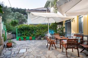 um pátio com uma mesa, cadeiras e um guarda-sol em Hotel Selini em Ayios Nikitas