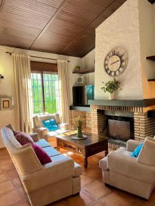 a living room with a fireplace and a clock on the wall at Complejo Rural Mirador de la Alcaidía in Hornachuelos +112 photos