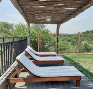 two benches on a deck with a wooden roof at Cabaña 3 in Bialet Massé