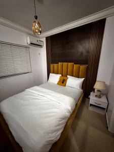 1 dormitorio con 1 cama blanca grande y cabecero en Daisies, en Lekki