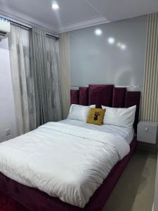 a large bed with white sheets and a yellow pillow at Daisies in Lekki