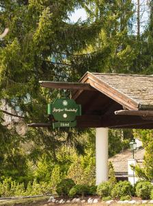 a green sign hanging from a roof of a house at House of Hütter - Wachtelhof Hotel & Spa in Maria Alm am Steinernen Meer