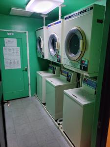 a laundry room with washers and dryers and a green wall at HOTEL SEAGULL - Vacation STAY 04622v in Izumi-Sano