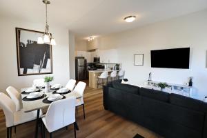 a living room with a black couch and a table and chairs at Central 3 Queen Beds,Double Garage,Disney+ in Edmonton