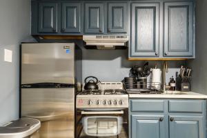 uma cozinha com armários azuis e um frigorífico de aço inoxidável em Apartment 224: Upper West Side em Nova York