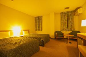 una camera d'albergo con due letti e un tavolo con sedie di HOTEL SEAGULL - Vacation STAY 86778v a Izumisano