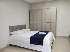 a bedroom with a large bed and a cabinet at Apartamentos aconchegante Aki in Cacoal