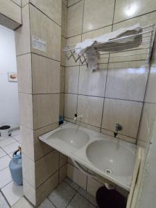 uma casa de banho com um lavatório e uma parede em azulejo em Seu Apto Praia da Costa Centro 4 Barato Não divide 2Q Completo Ar Cond Fogão Geladeira Excel Localização em Vila Velha