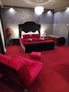 a bedroom with a large red bed and a couch at Skitnica Red door in Koprivnica