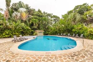 una piscina in un resort con sedie e alberi di Hotel Playa Westfalia a Puerto Limón