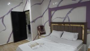 a bedroom with a bed and a purple and white wall at العيون شارع 24 نوفمبر قرب قروان in Laayoune