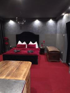 a bedroom with a bed with red sheets and pillows at Skitnica Red door in Koprivnica