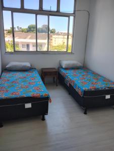 two beds in a room with two windows at Pousada Family in Salvador