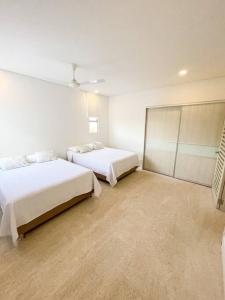 two beds in a room with white walls at Exclusiva casa en Baru con piscina y playa privada in Playa Blanca