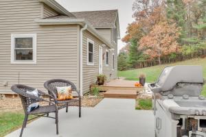 a patio with a grill and a chair next to a house at Lovely Hixton Home with Porch and Fire Pit! in Black River Falls