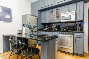 a kitchen with white cabinets and a counter with chairs at Apartment 282: Columbus Circle in New York