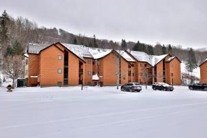 a row of houses in the snow with parked cars at Beautifully decorated 3 bedroom condo nestled Slopeside on Pico Mountain Ski-in Ski-out G101 in Killington