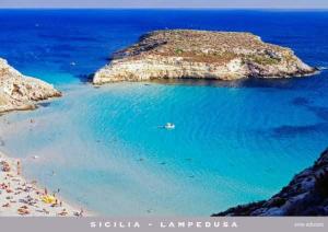 een strand met een stel mensen in het water bij Blu Mare Lampedusa Bed And Breakfast in Lampedusa