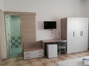 a room with a desk with a television and a shower at Blu Mare Lampedusa Bed And Breakfast in Lampedusa