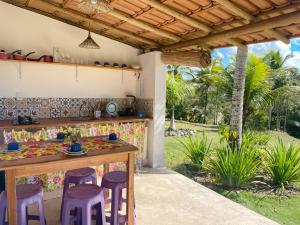 uma cozinha com uma mesa e bancos num quintal em Canto do Mar - Chalés com vista pro Mar - Cumuruxatiba em Cumuruxatiba