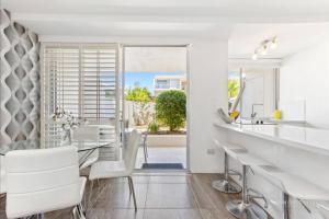 a dining room with a table and white chairs at Absolute Hastings Street Noosa Suite in Noosa Heads