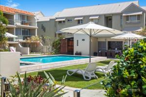 a house with a swimming pool and two chairs and an umbrella at Absolute Hastings Street Noosa Suite in Noosa Heads