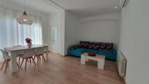 a living room with a table and a blue couch at Apartamento nuevo en Terrassa Centro in Terrassa