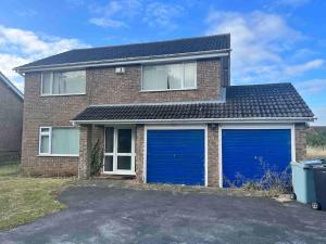 a brick house with two blue garage doors at Impressive Large 6 Bed House FREE WI FI in Lincolnshire