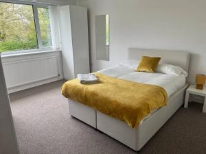 a bedroom with a bed with a yellow blanket on it at Impressive Large 6 Bed House FREE WI FI in Lincolnshire