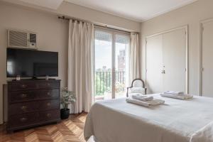 1 dormitorio con 1 cama, TV y ventana en Fliphaus Libertador 1100 - 3 Bd Recoleta en Buenos Aires