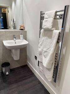 a bathroom with a sink and a mirror and towels at Stunning Flat with Parking Free near Sutton Station in Cheam