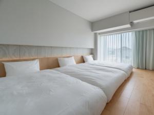 Cama blanca grande en habitación con ventana grande en ITOMACHI HOTEL 0 - Vacation STAY 97802v, en Saijo